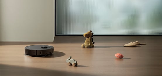 Robot sprzątający odkurza podłogę obok rozrzuconych zabawek